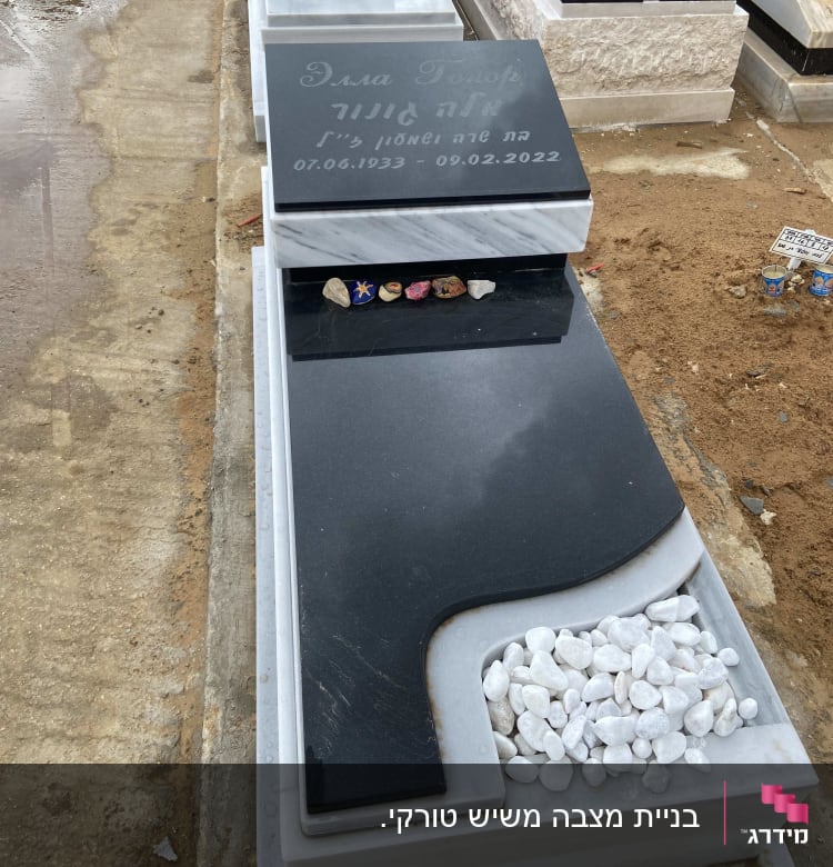 מצבה שחורה עם אבנים לבנות קטנות